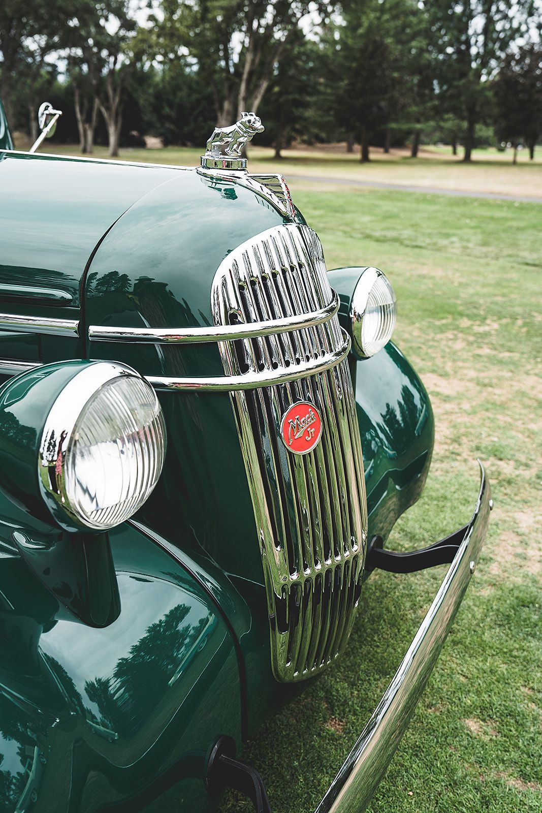 A green car with a chrome grille is parked in a grassy field.