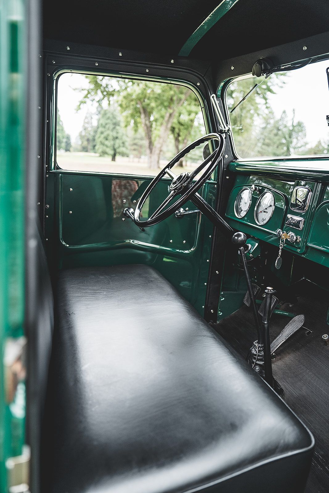 The interior of a green truck with a black seat and steering wheel.