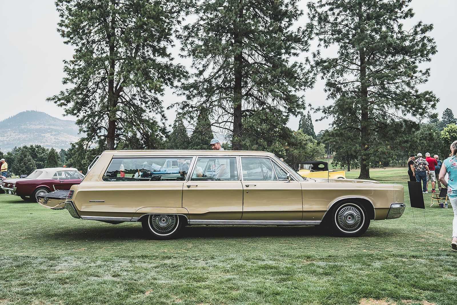 A vintage station wagon is parked in a grassy field.