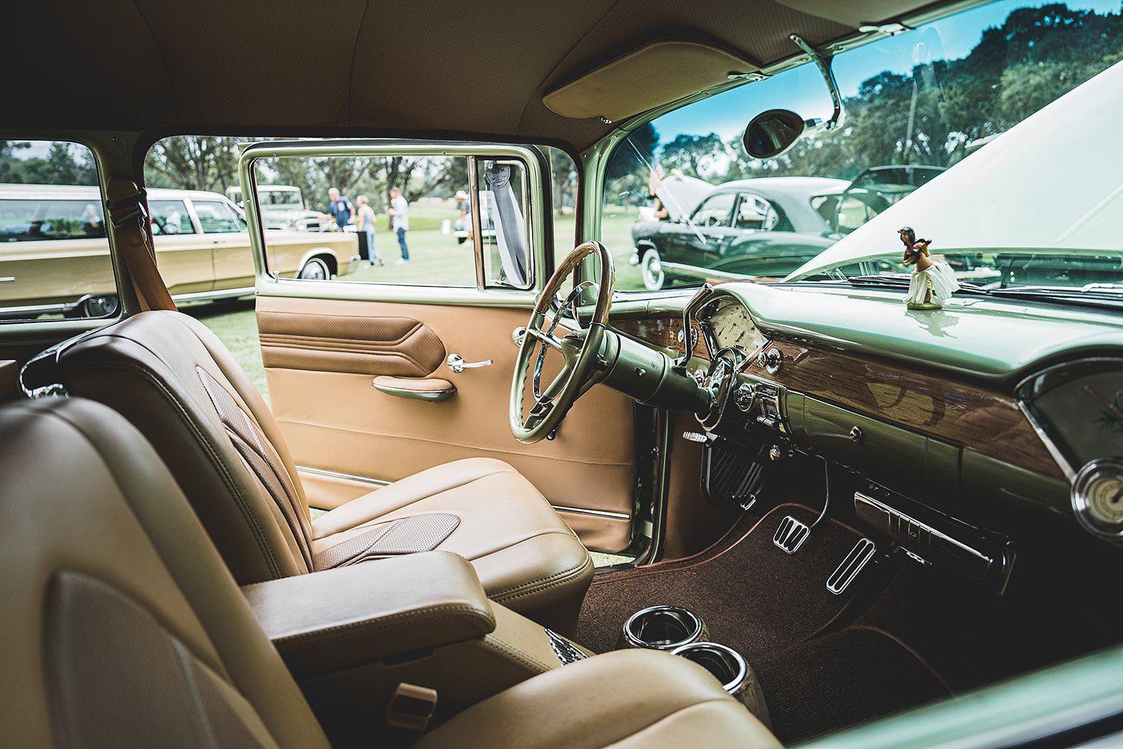 The interior of an old car with brown leather seats and a steering wheel.