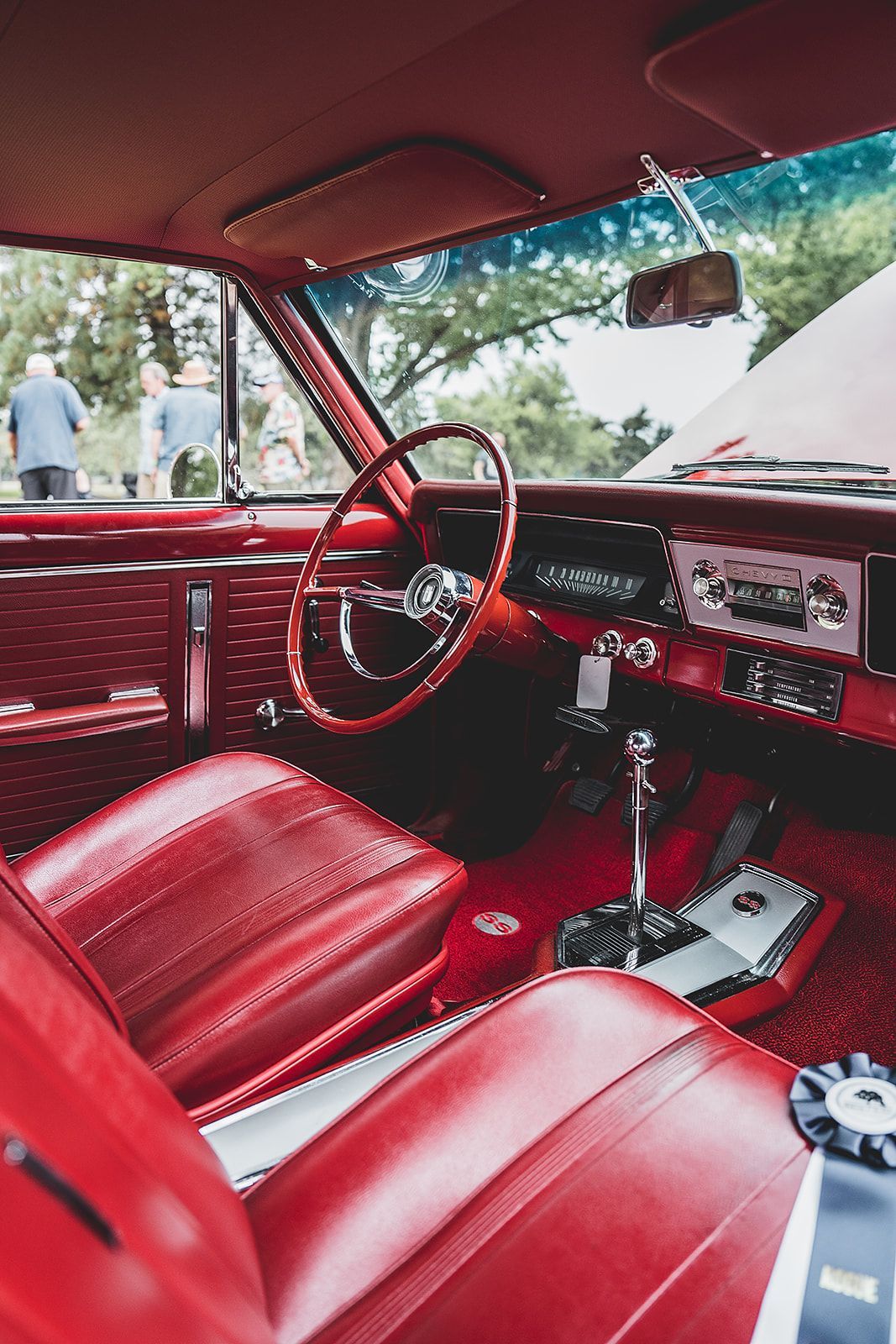 The interior of a red car with red seats and a wooden steering wheel.
