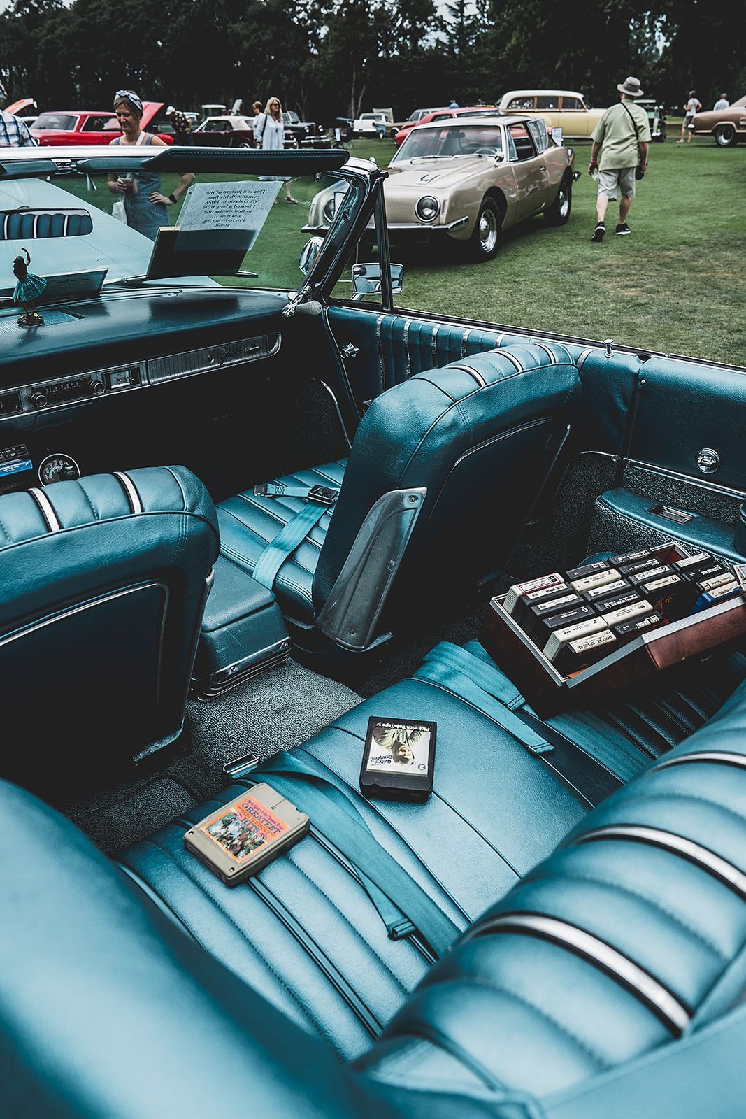 The inside of a blue car with a book on the seat.