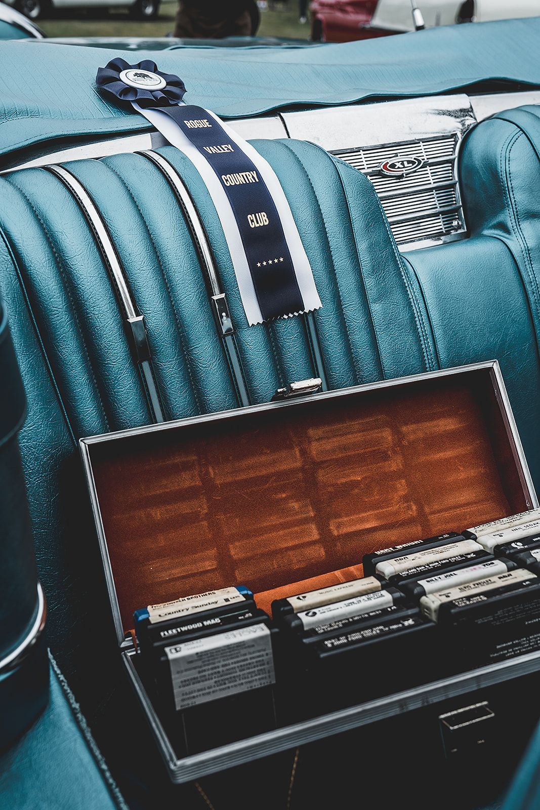A box of cassette tapes is sitting in the back seat of a car.