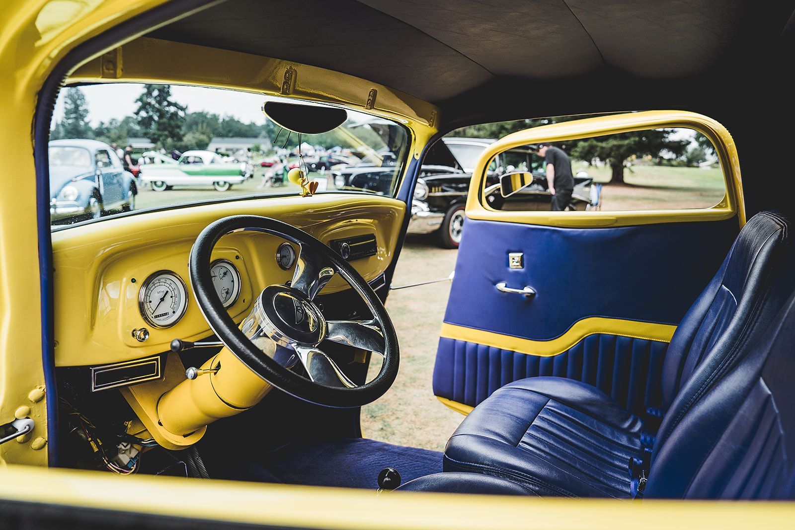The interior of a yellow car with blue seats and a steering wheel.