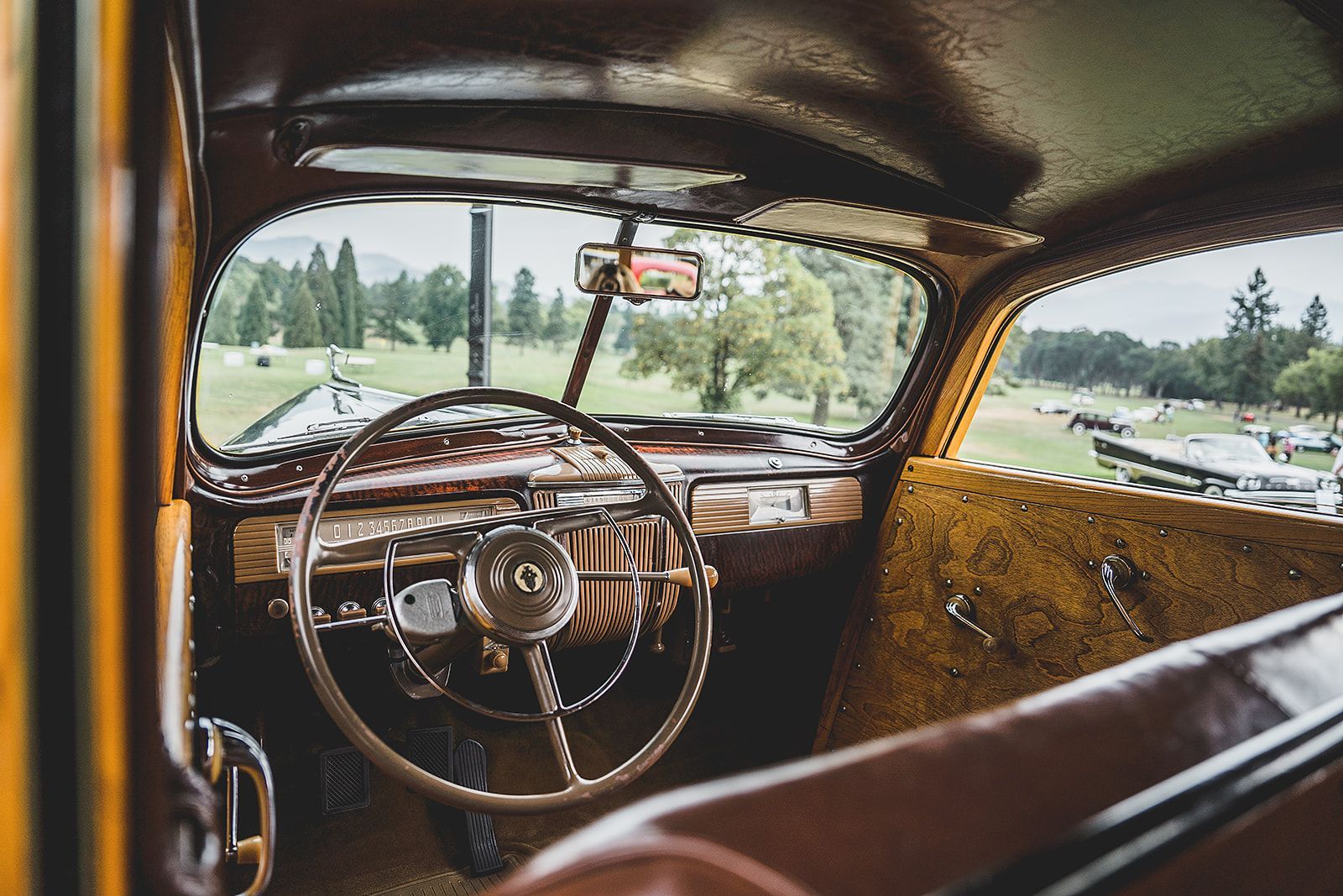 The interior of an old car with a steering wheel and a dashboard.