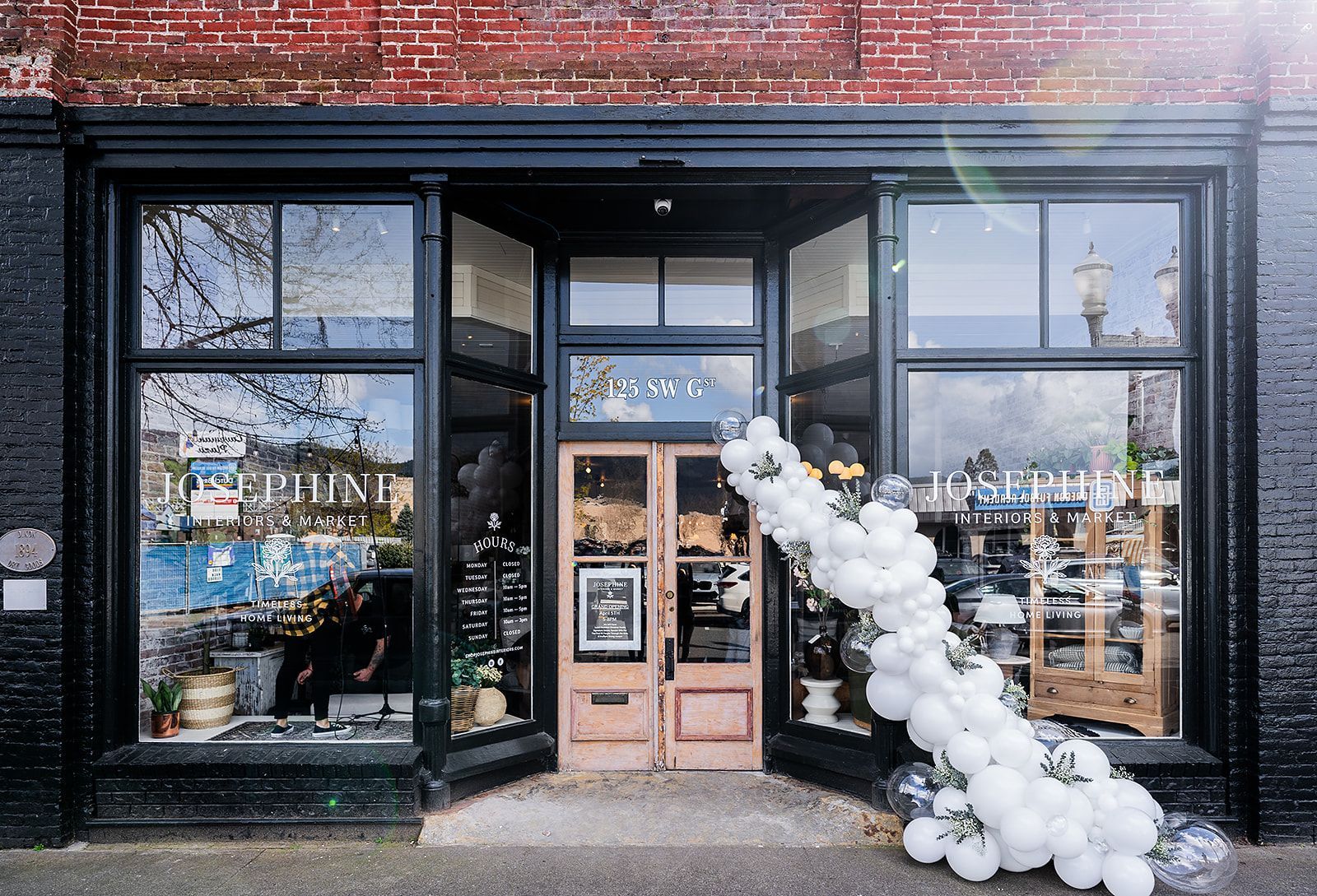 A store front with a bunch of white balloons in front of it.