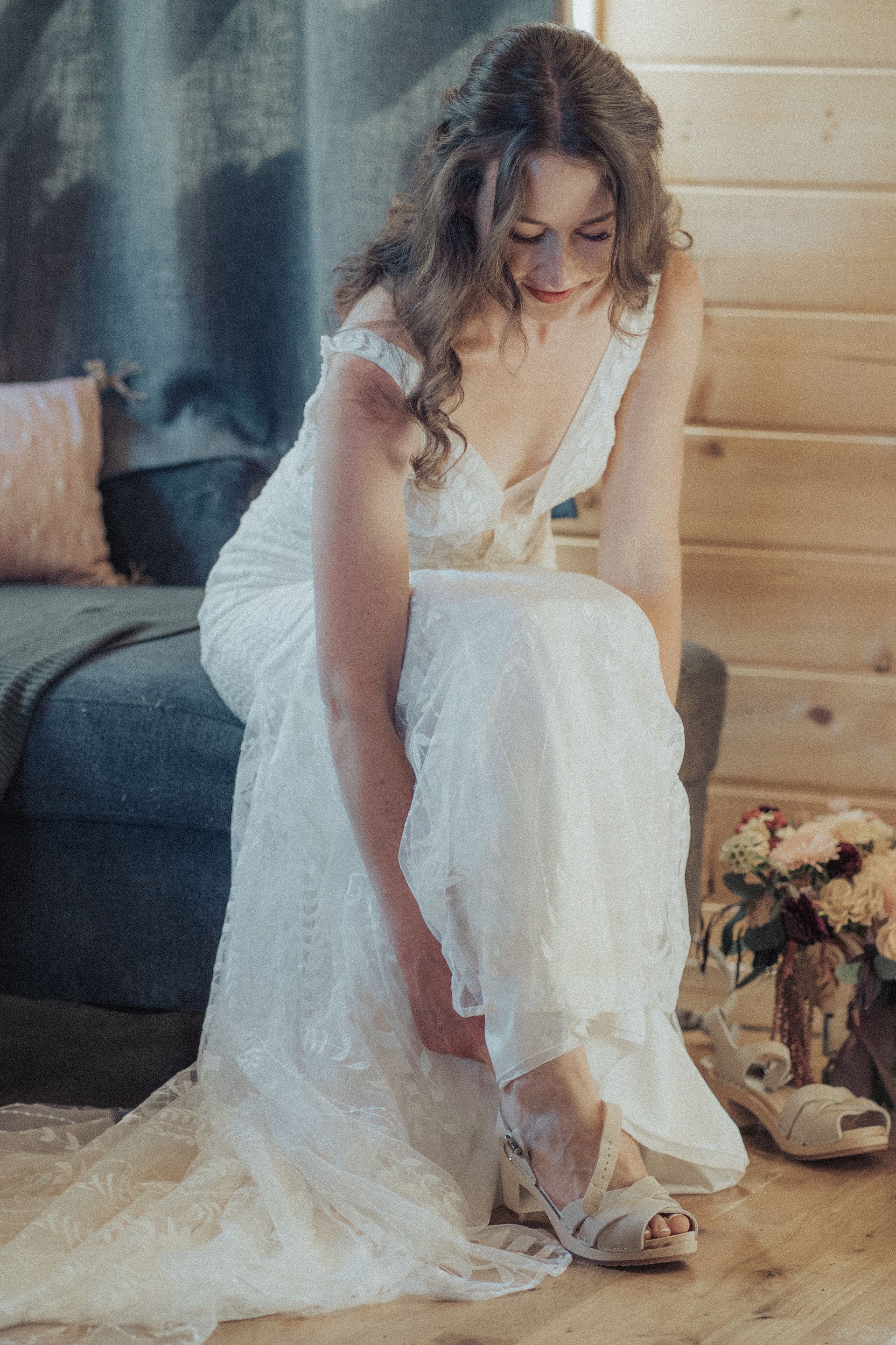 A woman in a wedding dress is putting on her shoes.
