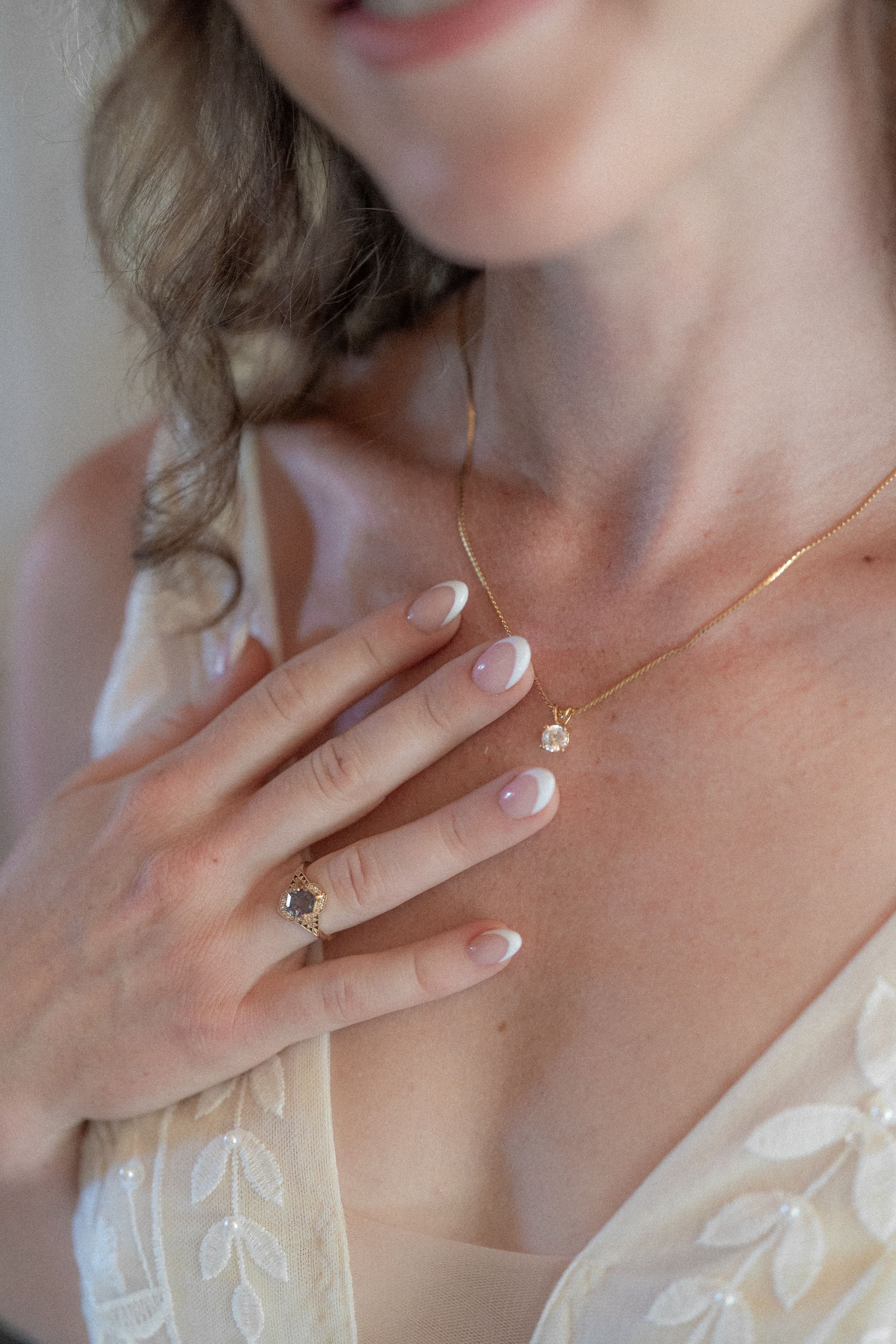 A woman is wearing a necklace and a ring on her finger.
