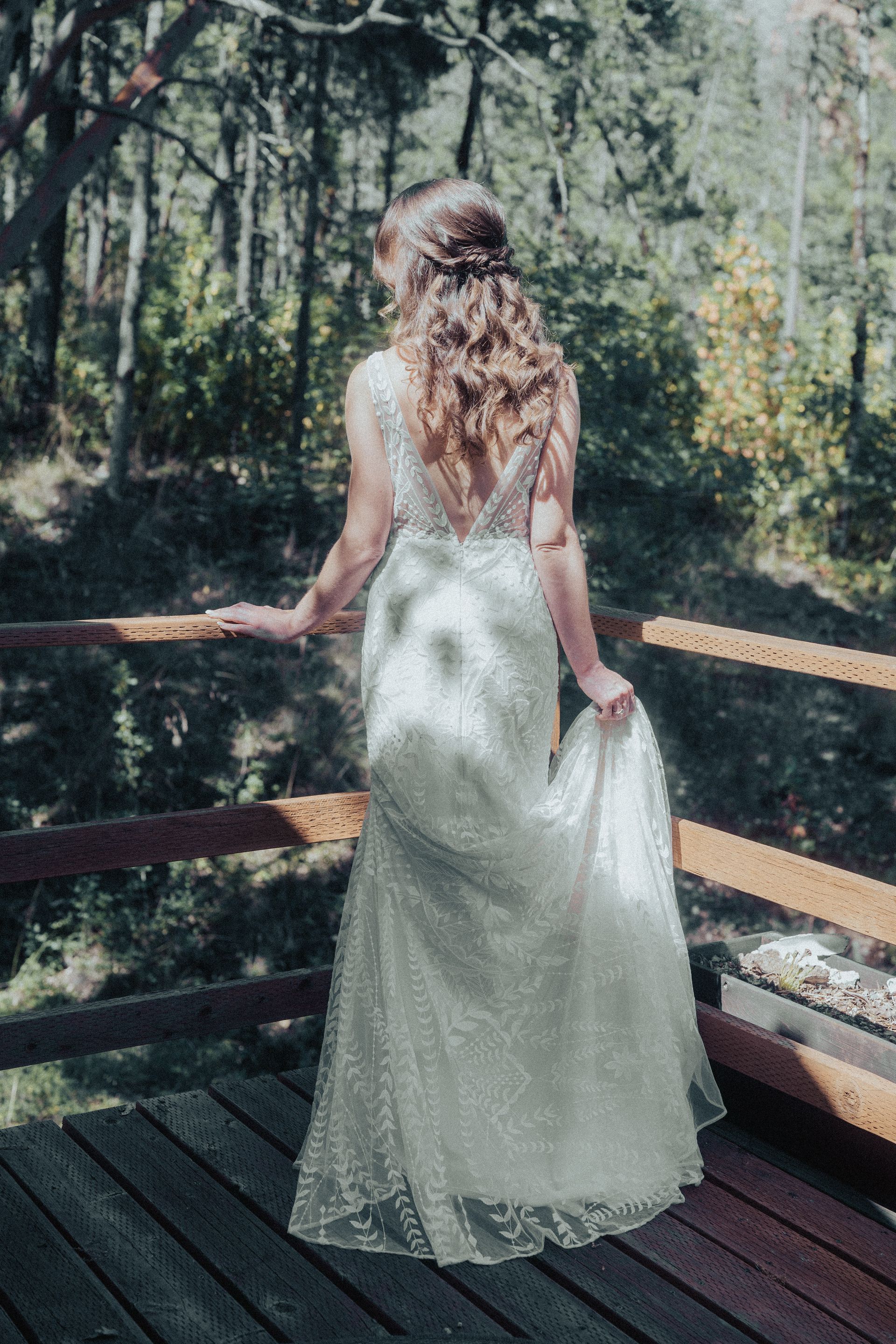 A woman in a wedding dress is standing on a wooden deck.