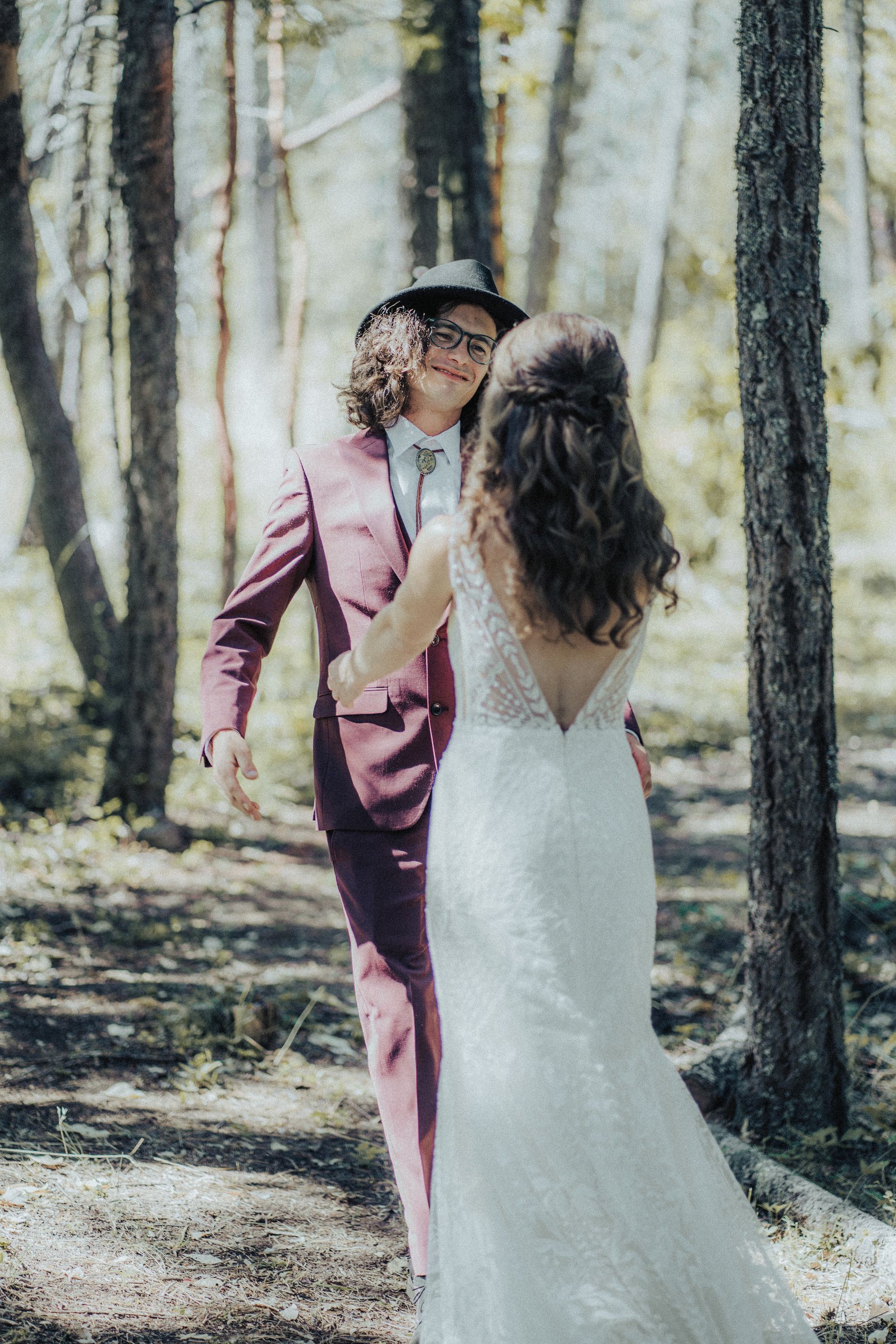A bride and groom are dancing in the woods.