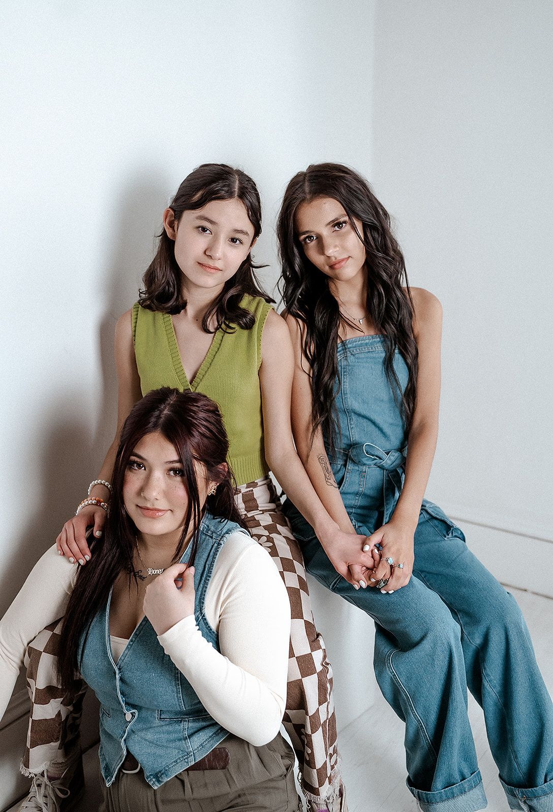Three young women are sitting next to each other in a room.