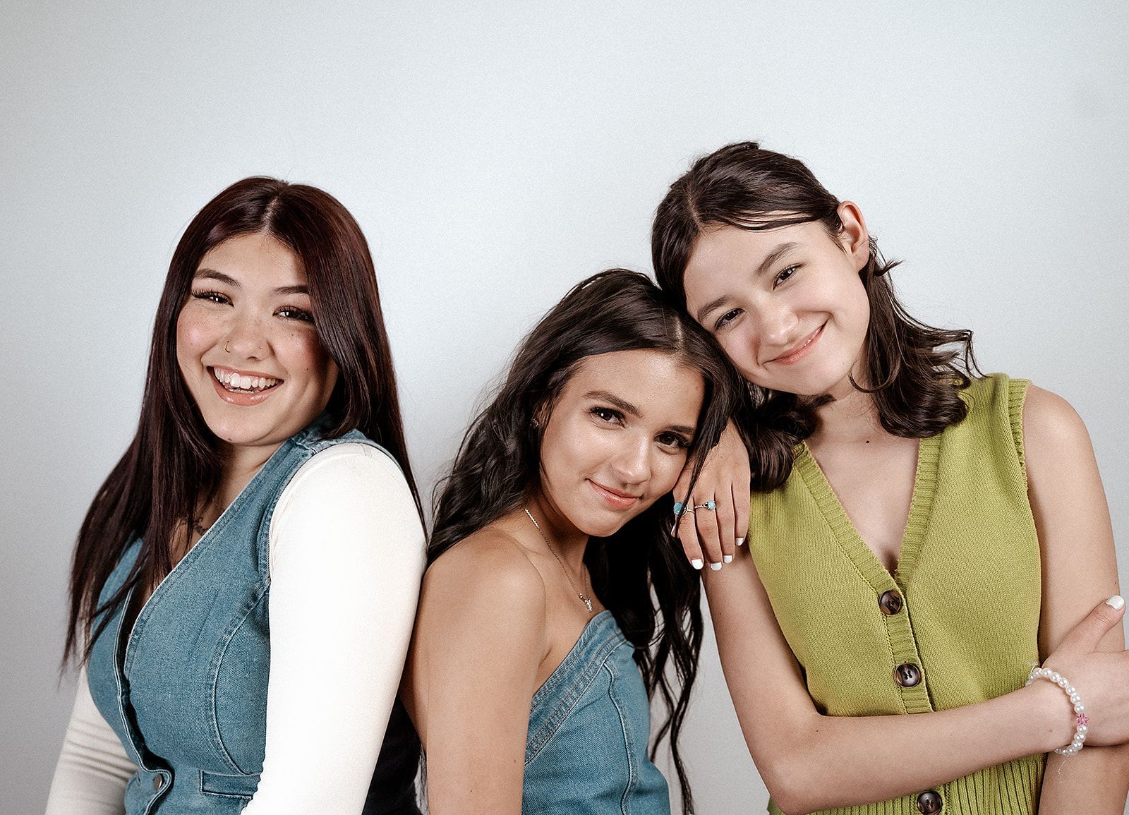 Three young women are posing for a picture together and smiling.