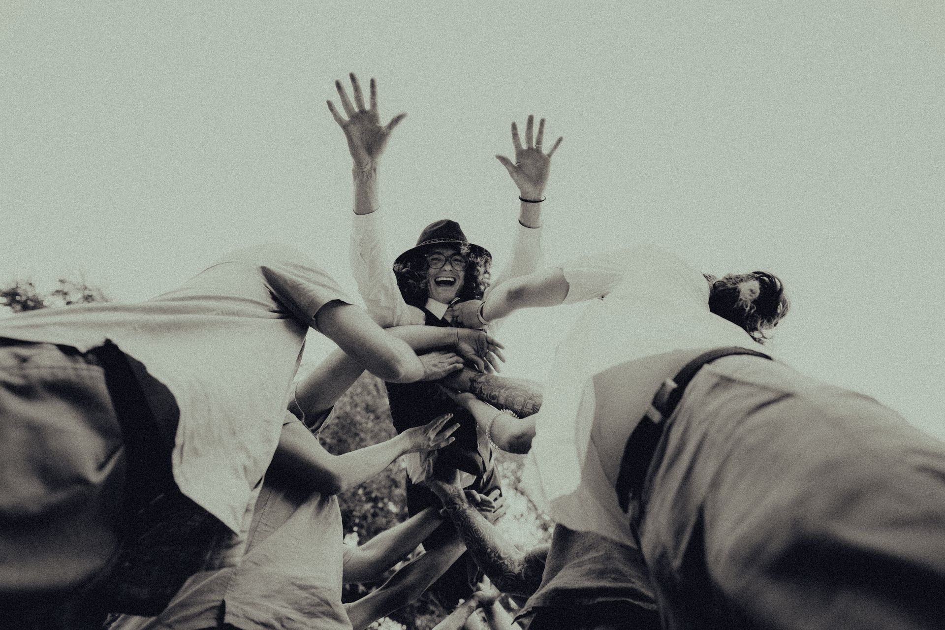 A group of people are standing in a pile with their hands in the air.