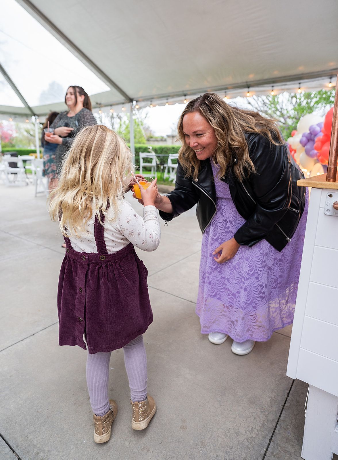 A woman in a purple dress is standing next to a little girl in a purple dress.