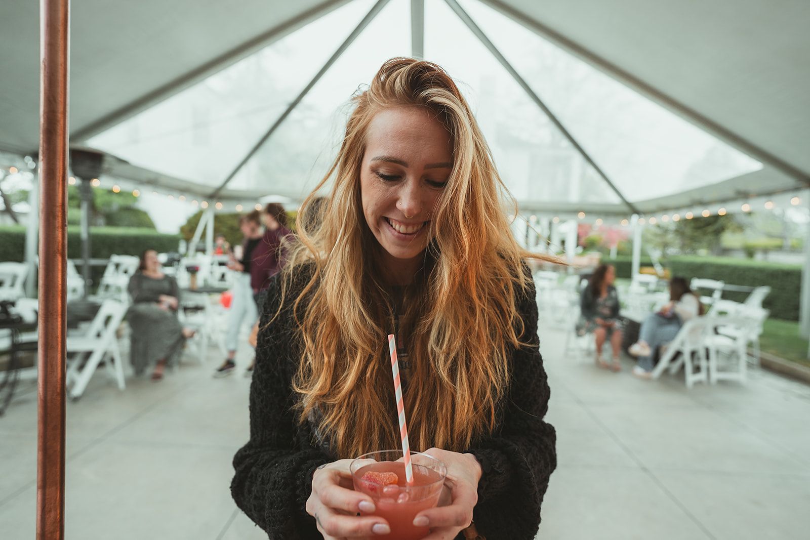 A woman is holding a glass of watermelon juice with a straw.
