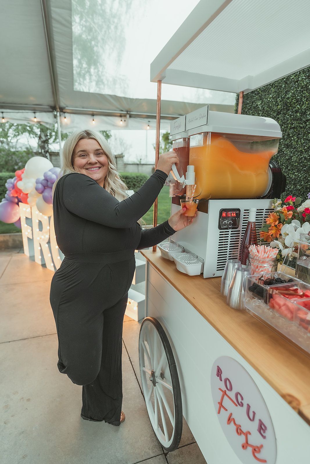 A woman is pouring a drink from a dispenser on a cart.