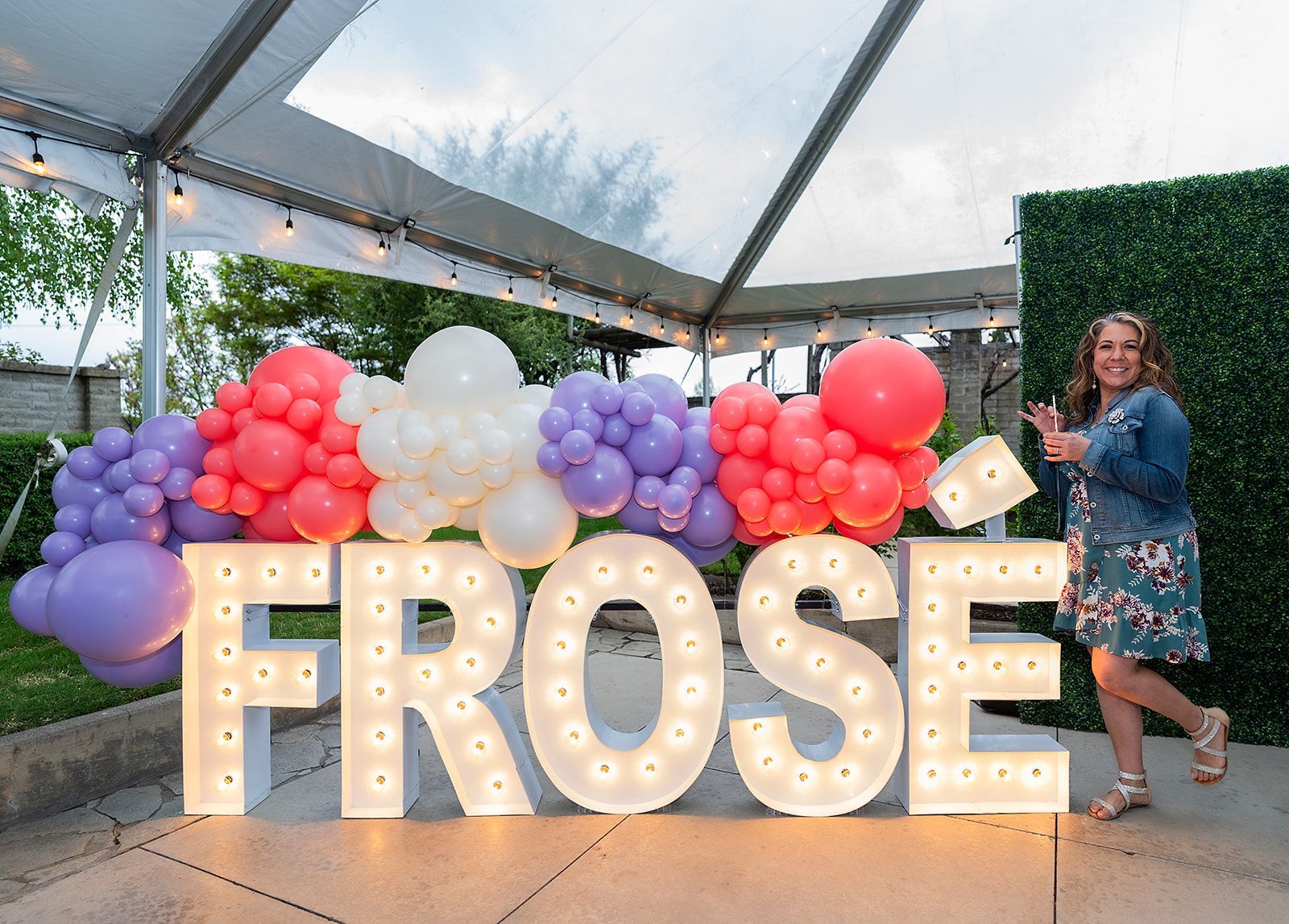 A woman is standing in front of a large sign that says frose.
