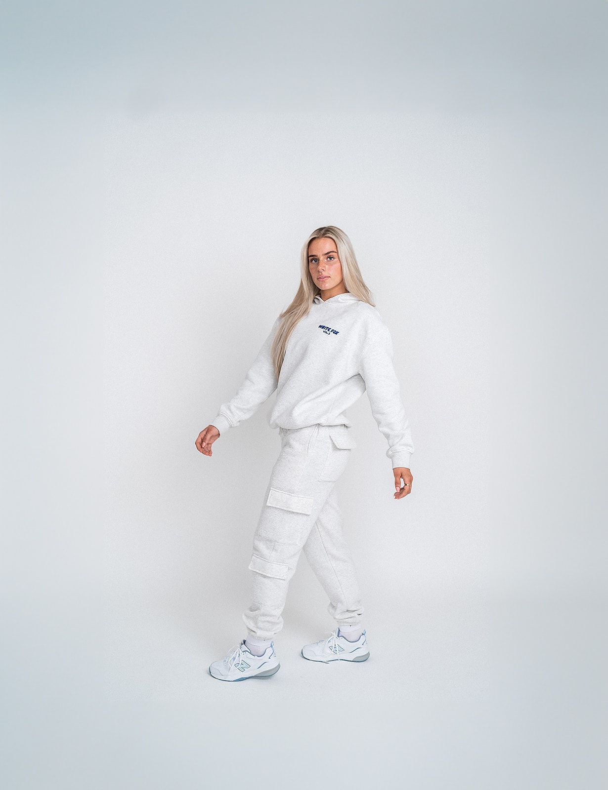 A woman is wearing a white sweatshirt and white cargo pants.