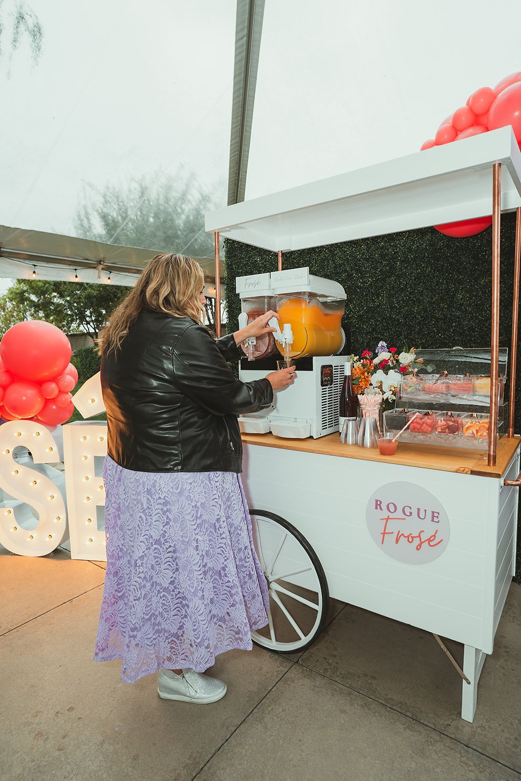 A woman is pouring orange juice into a cart.