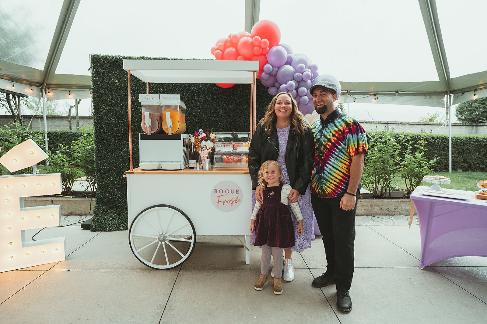 A man , woman and child are standing in front of a popcorn cart.