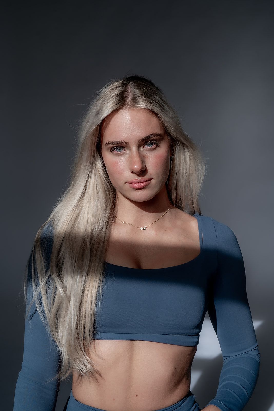 A woman with long blonde hair is wearing a blue crop top and blue pants.