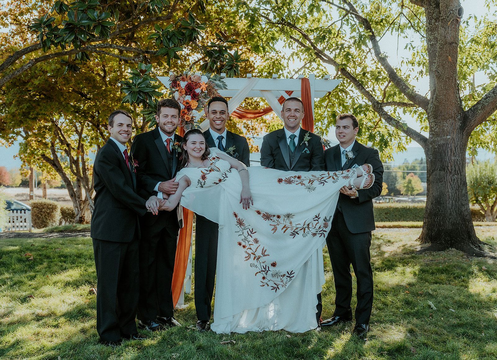 A bride and groomsmen are posing for a picture with their wedding party.