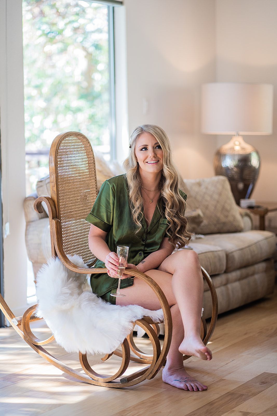 A woman is sitting in a rocking chair holding a glass of champagne.