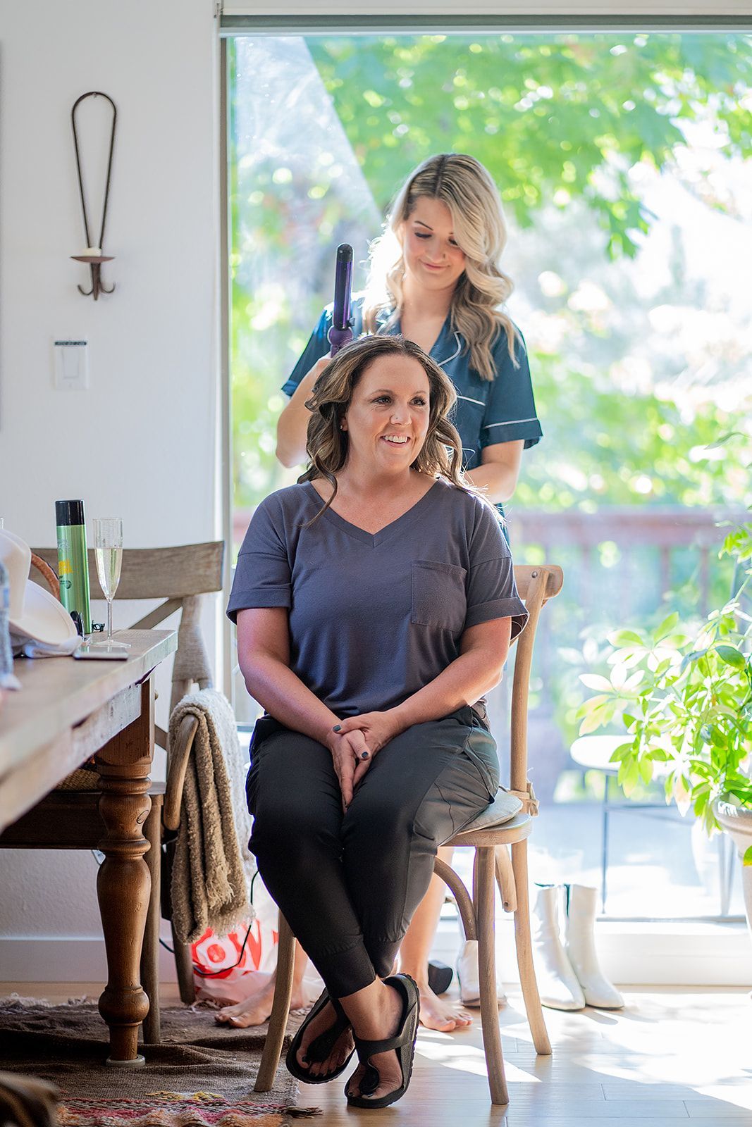 A woman is sitting in a chair getting her hair done by another woman.