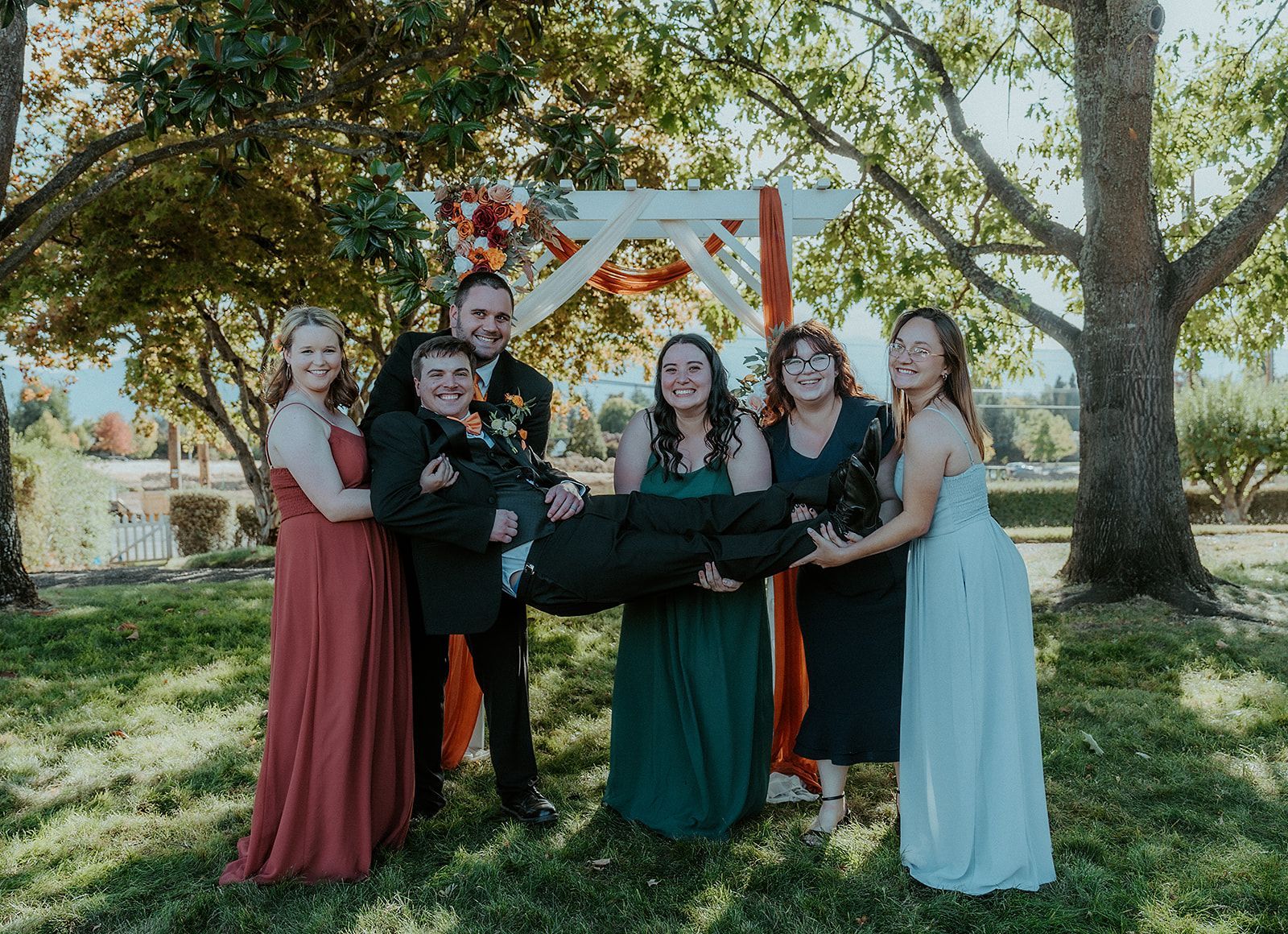 The groom and the bridesmaids are posing for a picture with their wedding party.