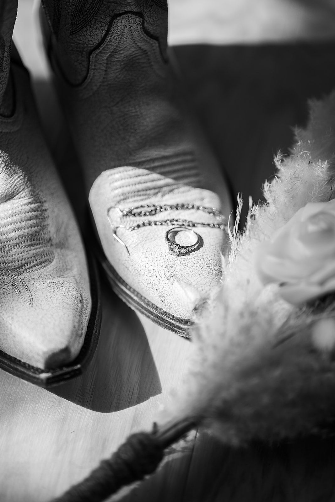 A pair of cowboy boots with a wedding ring on the toe.
