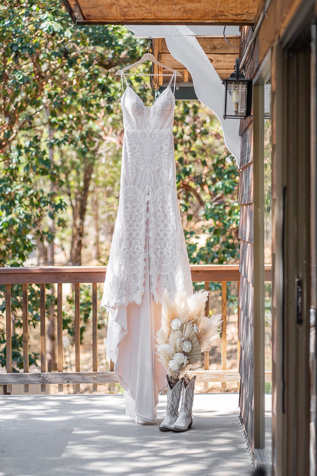 A wedding dress and cowboy boots are hanging on a balcony.