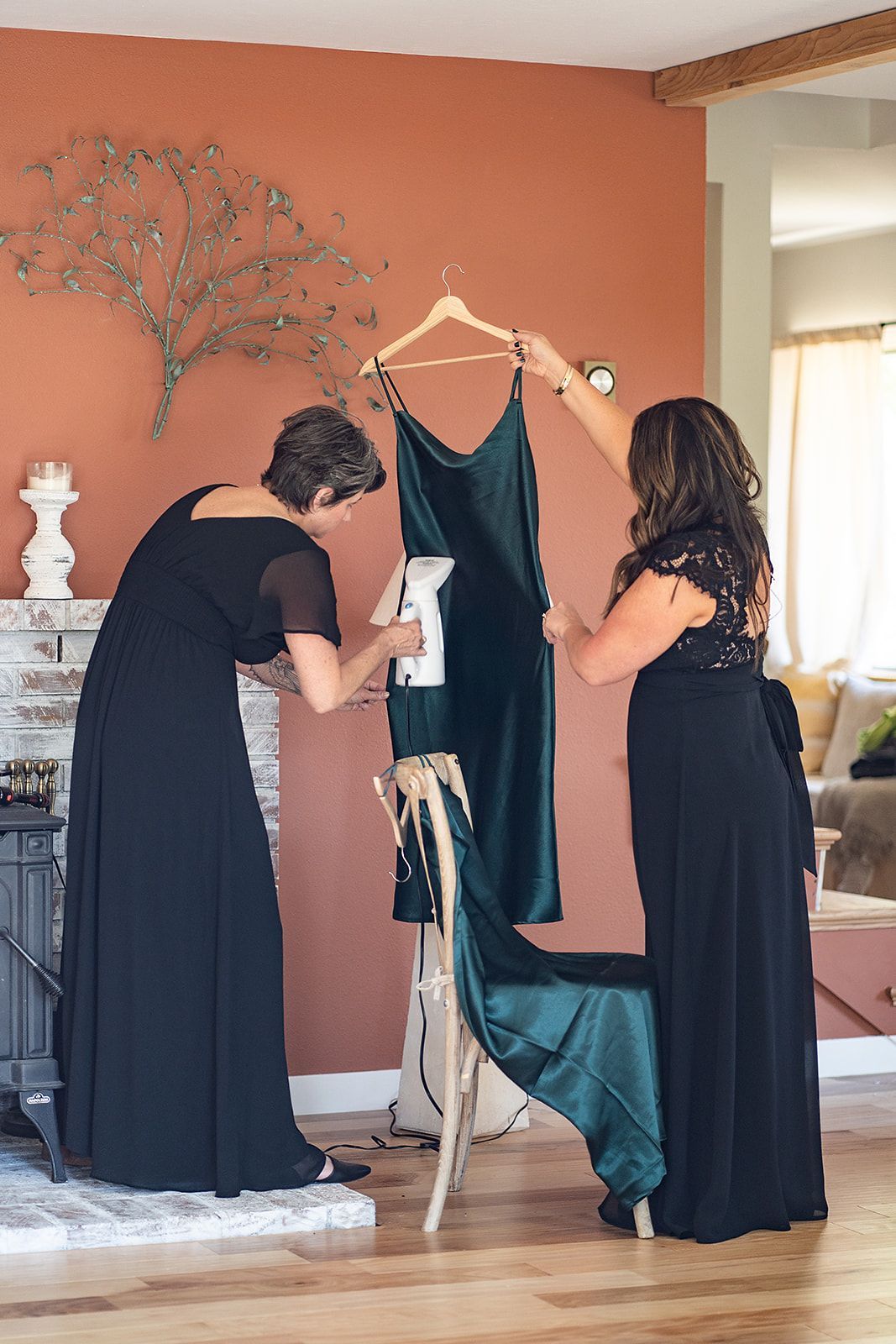 Two women are ironing a dress in a living room.