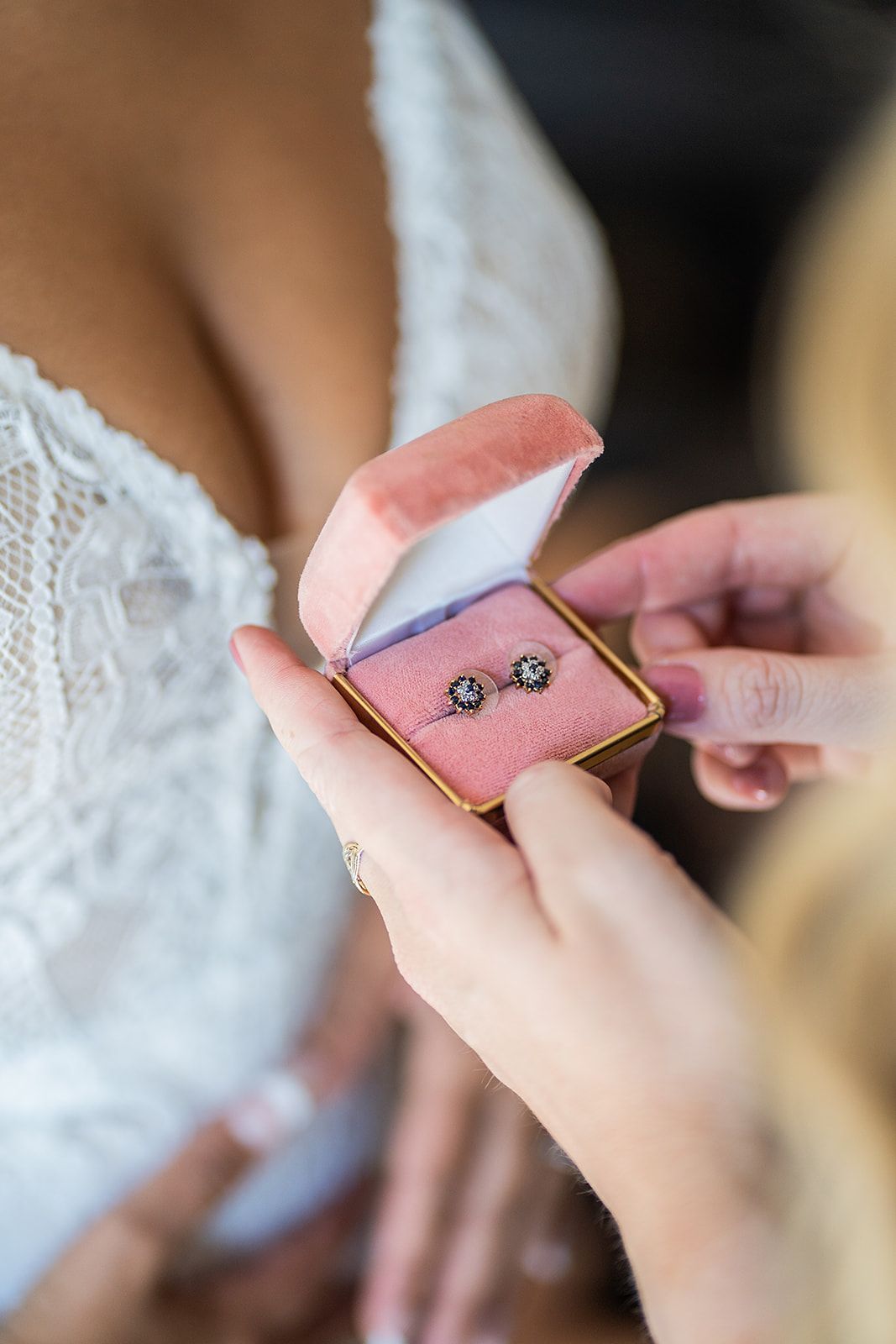 A woman is holding a pink box with earrings in it.