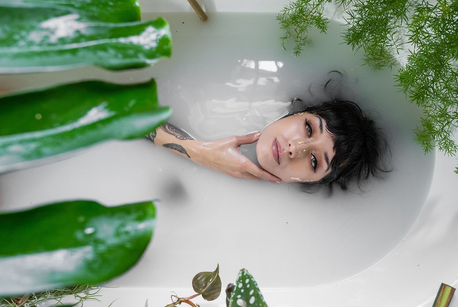 A woman is laying in a bathtub filled with milk and leaves.