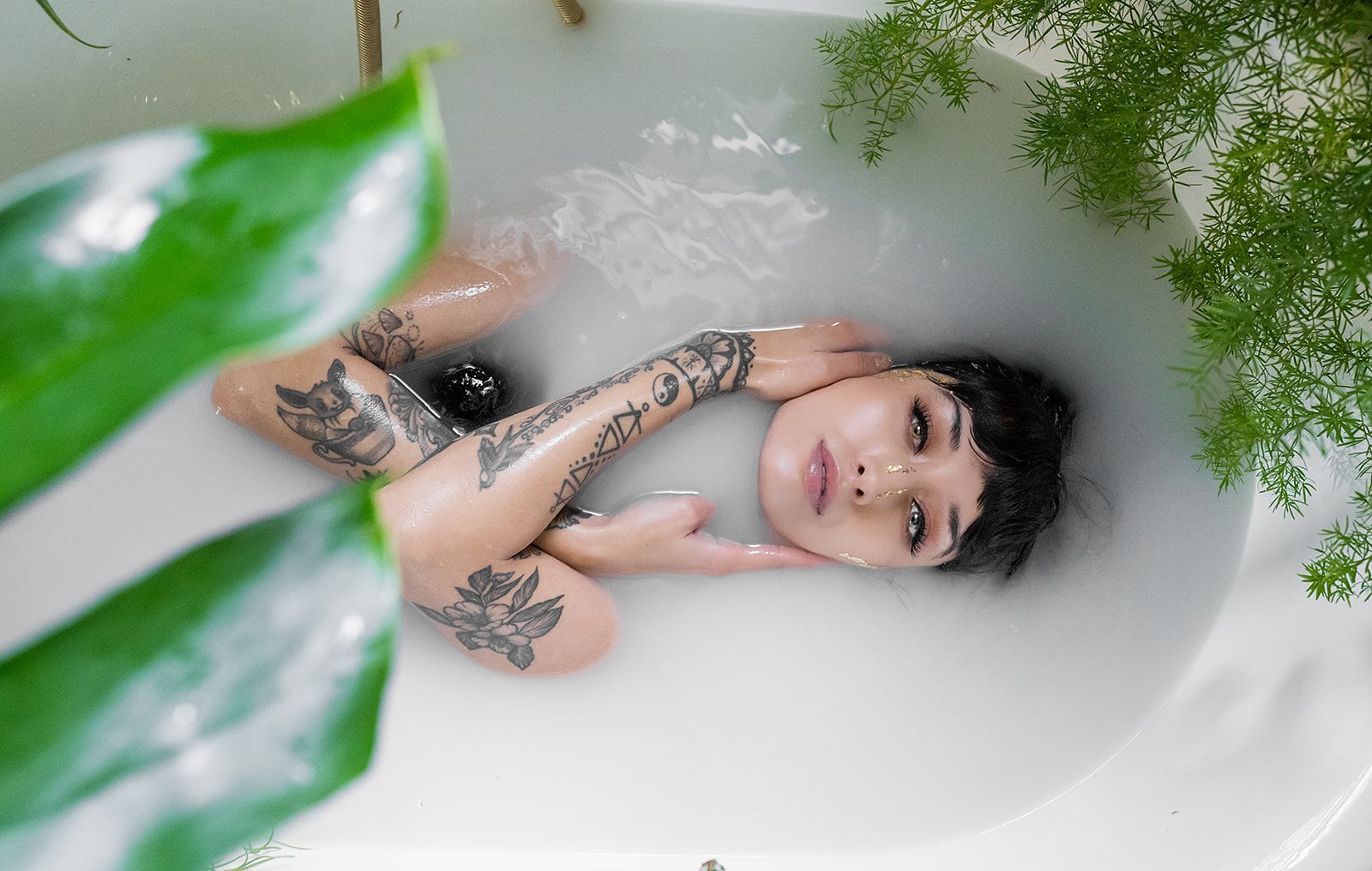 A woman is laying in a bathtub filled with milk.