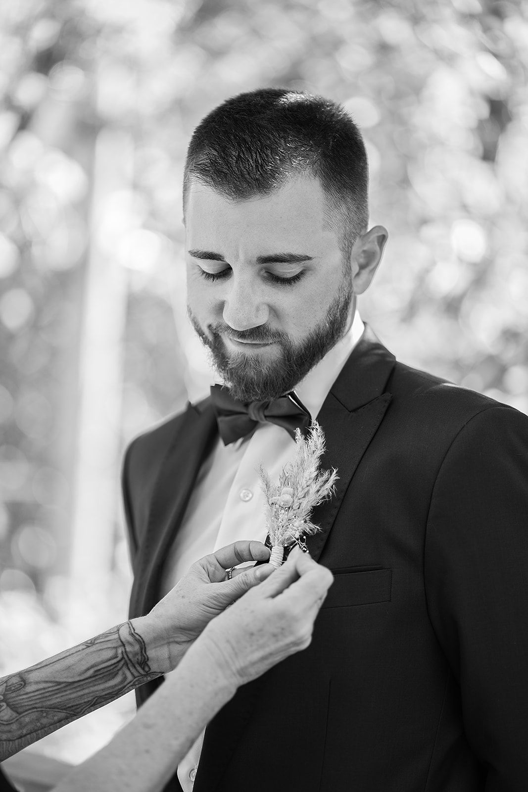 A black and white photo of a man in a suit getting ready for his wedding.