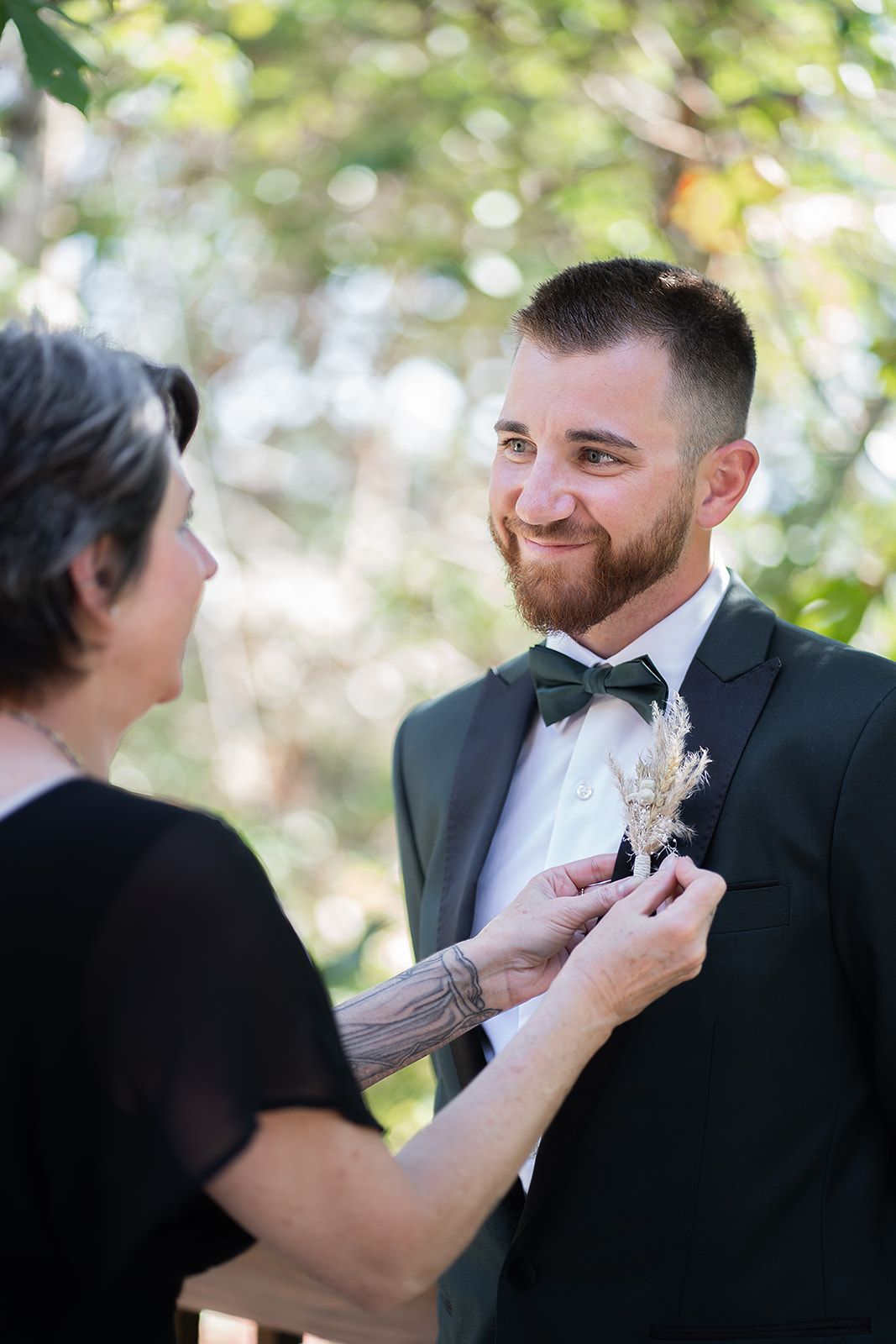 A woman is putting a flower in the pocket of a man in a suit.