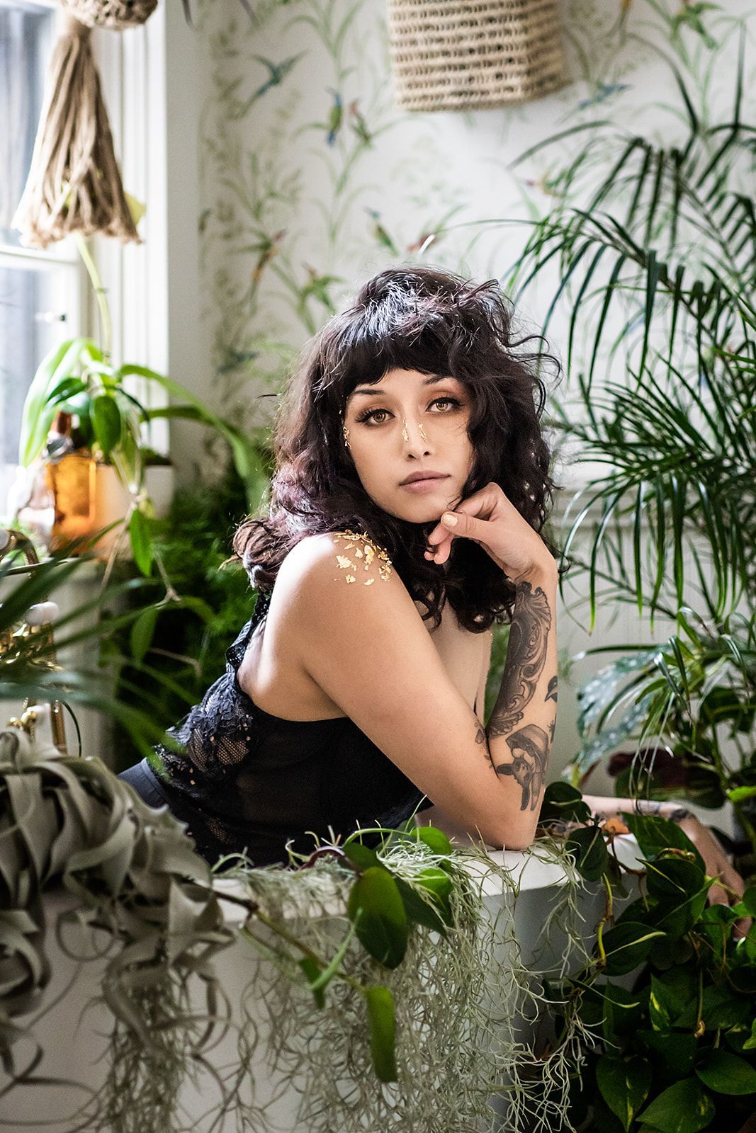 A woman is sitting in a bathtub surrounded by plants.