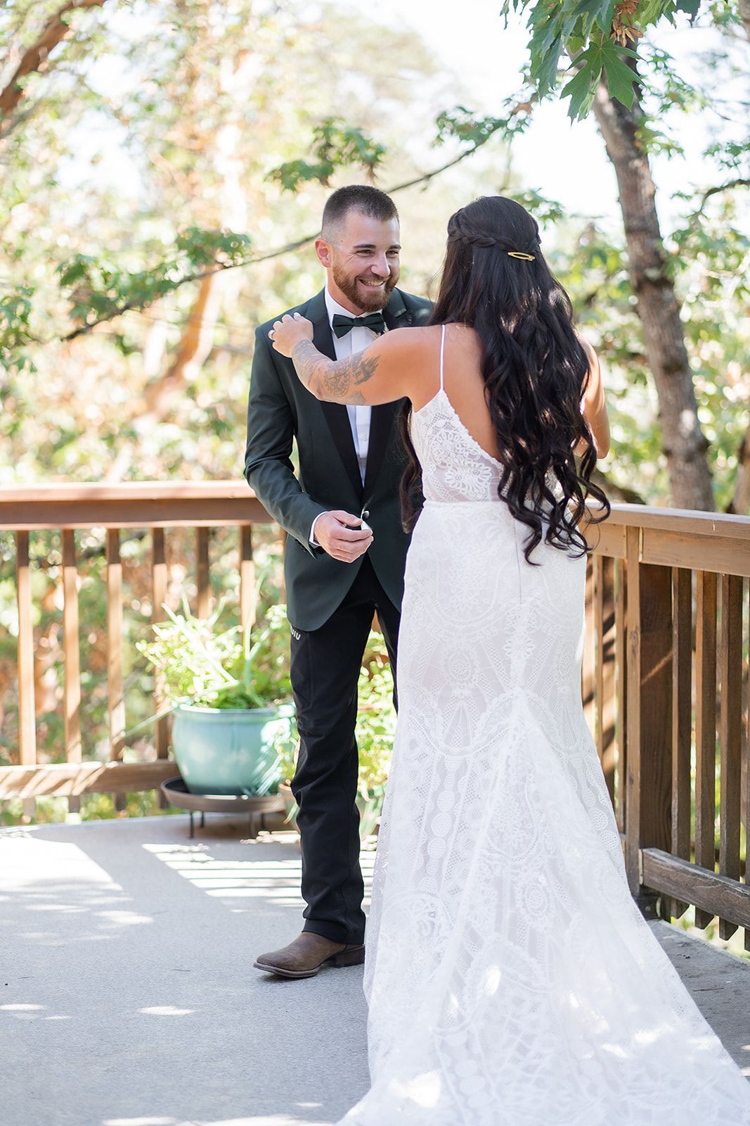 A bride and groom are hugging each other on a deck.