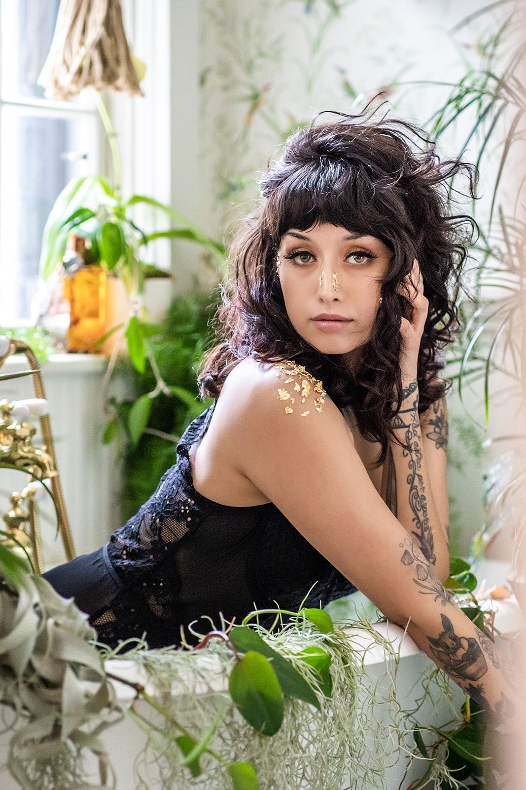 A woman is sitting in a bathtub surrounded by plants.