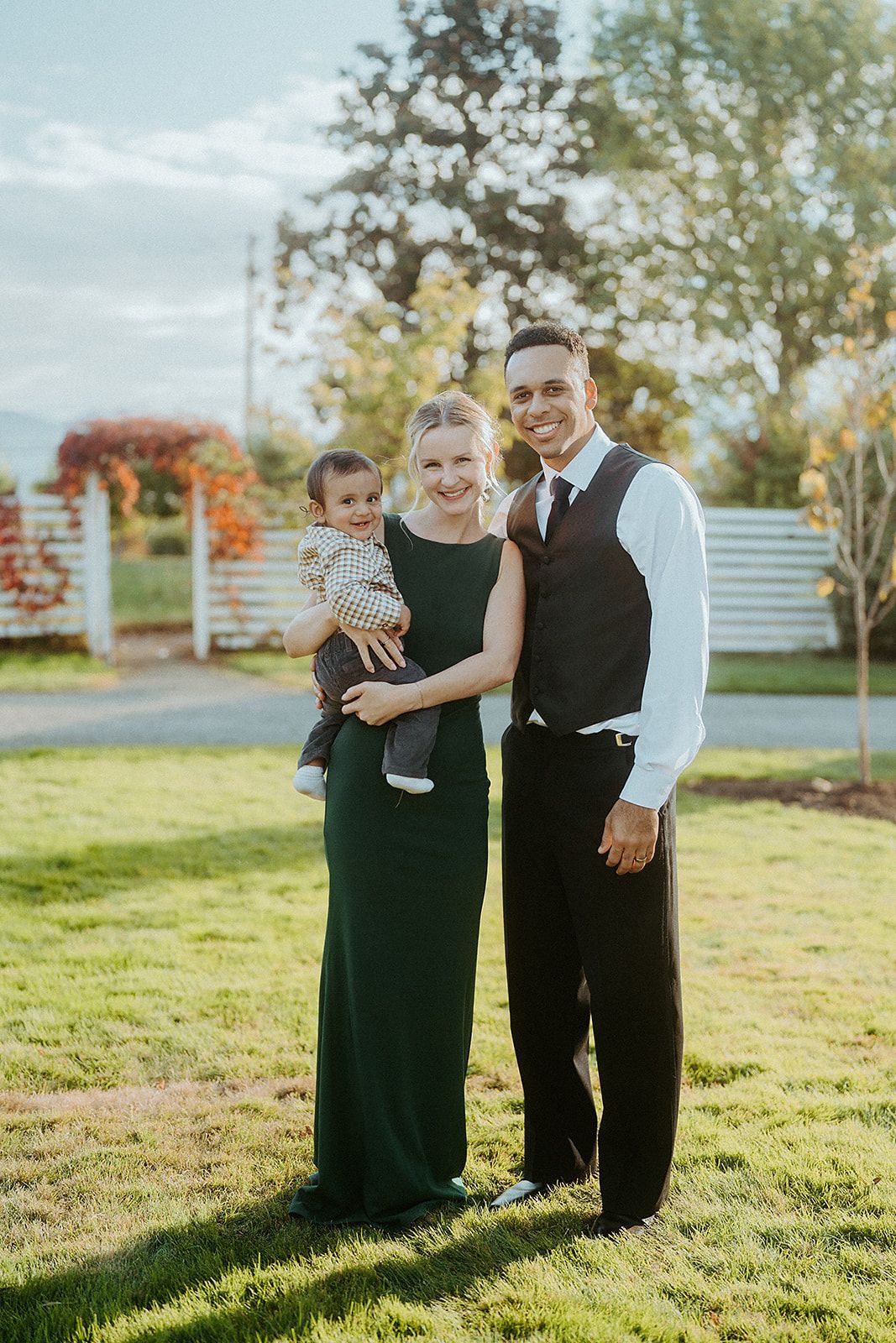 A man and woman are posing for a picture with a baby at a wedding in southern oregon.