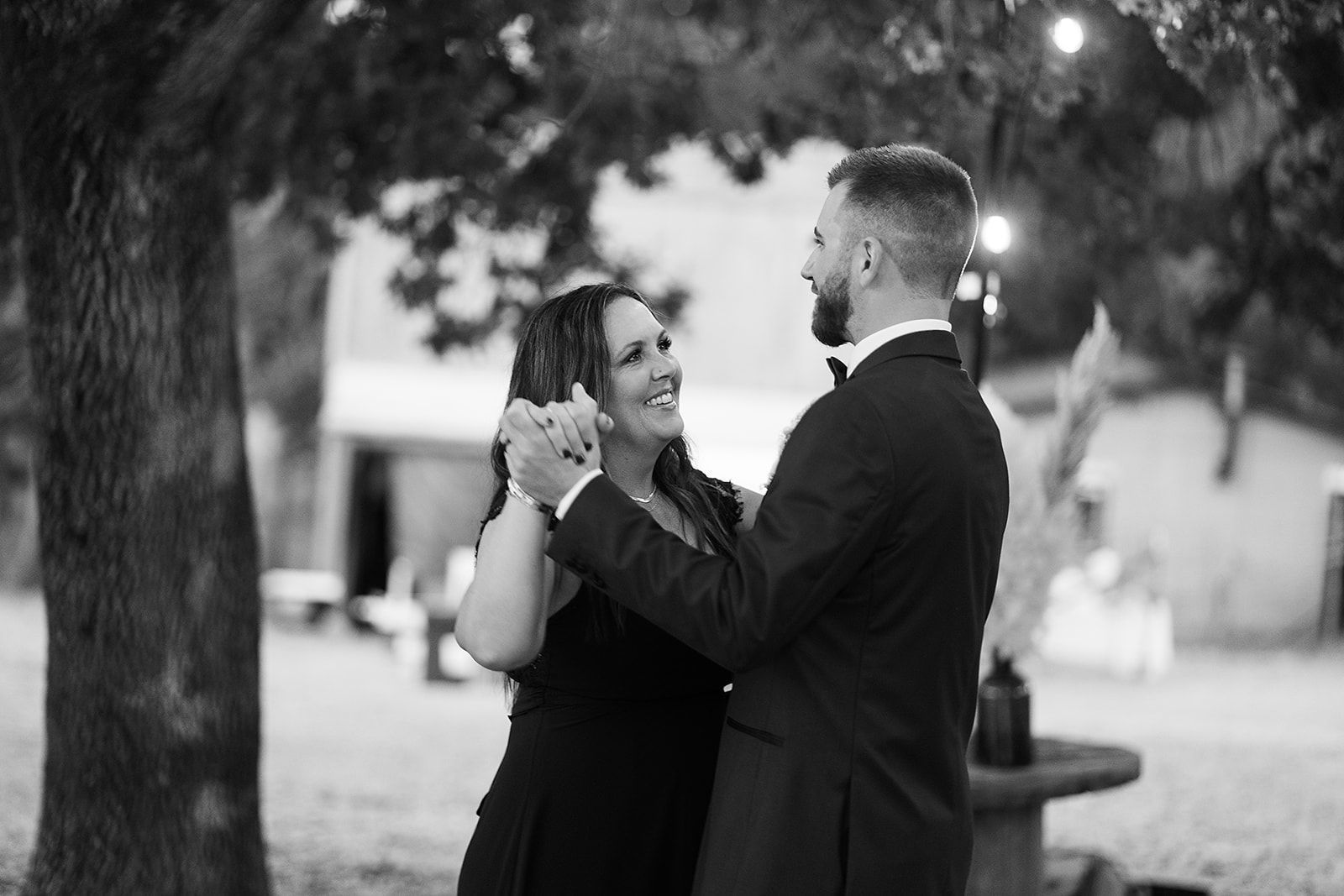 A black and white photo of a man and woman dancing under a tree.