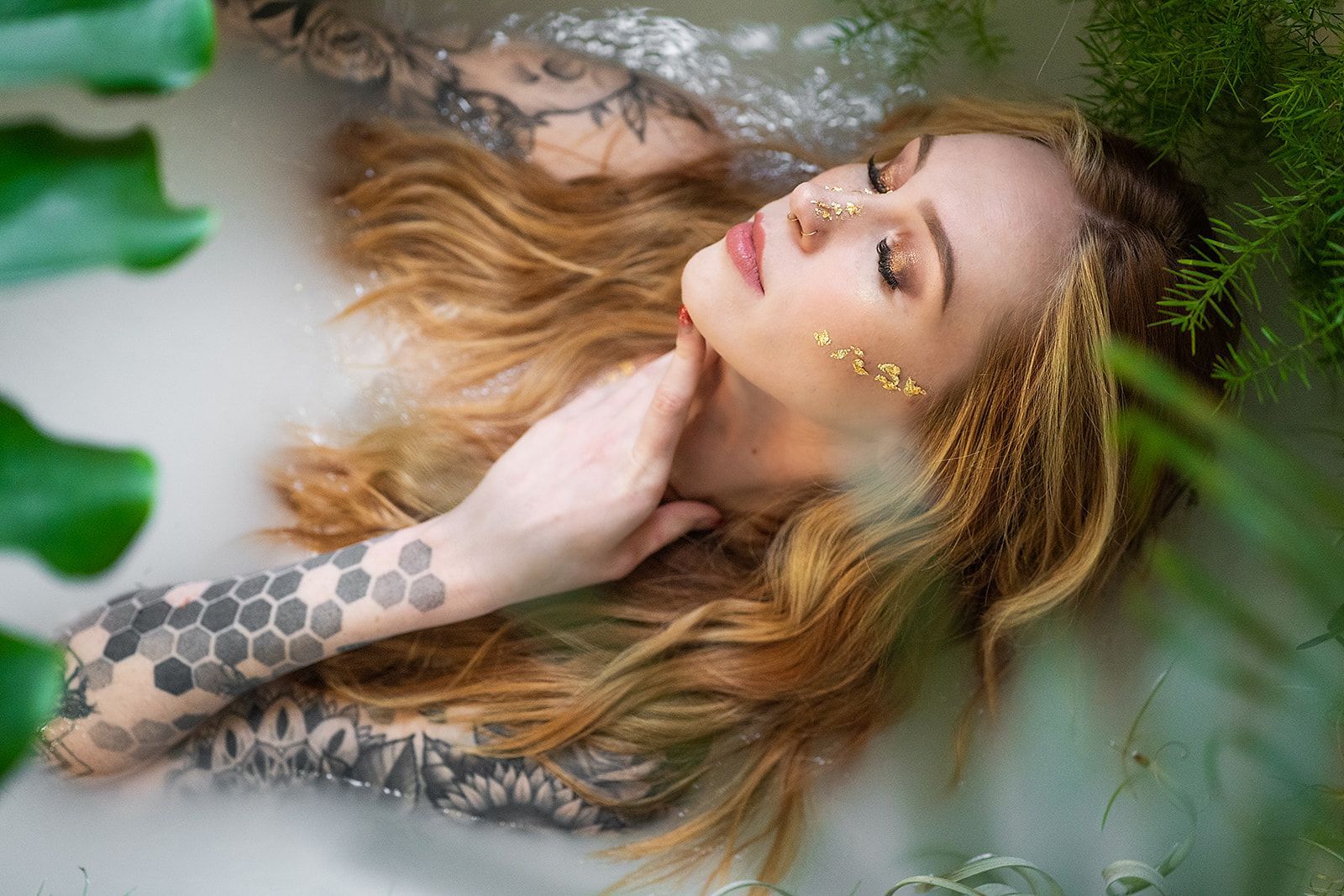 A woman is laying in a bathtub filled with milk and leaves.