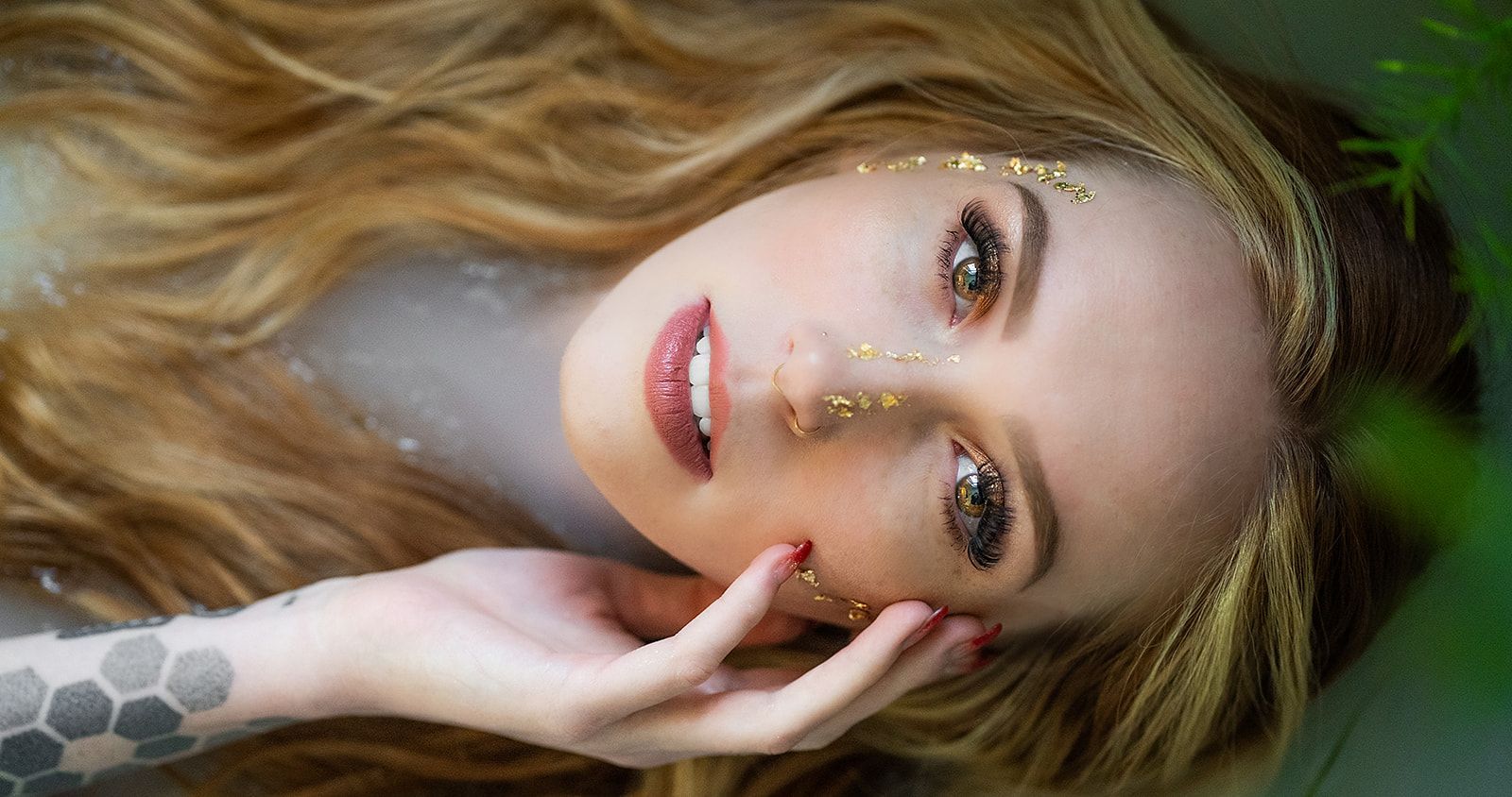 A woman is laying in a bathtub with a tattoo on her arm.