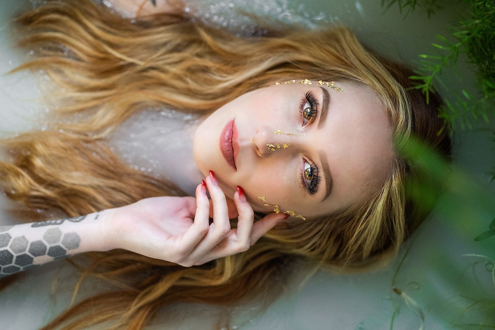 A woman is laying in a bathtub with her head in the water.