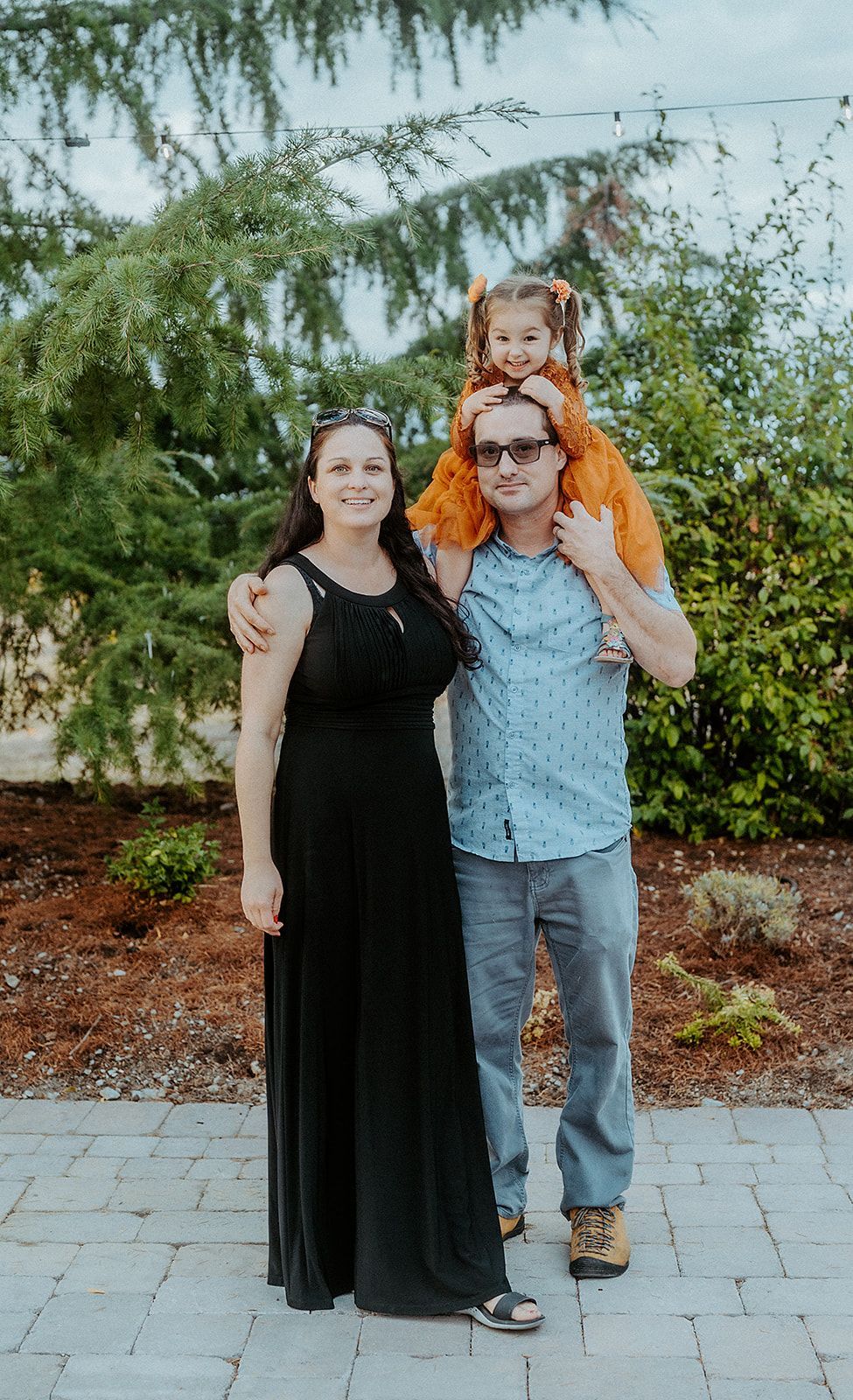 A man and woman are standing next to each other with a little girl on their shoulders.