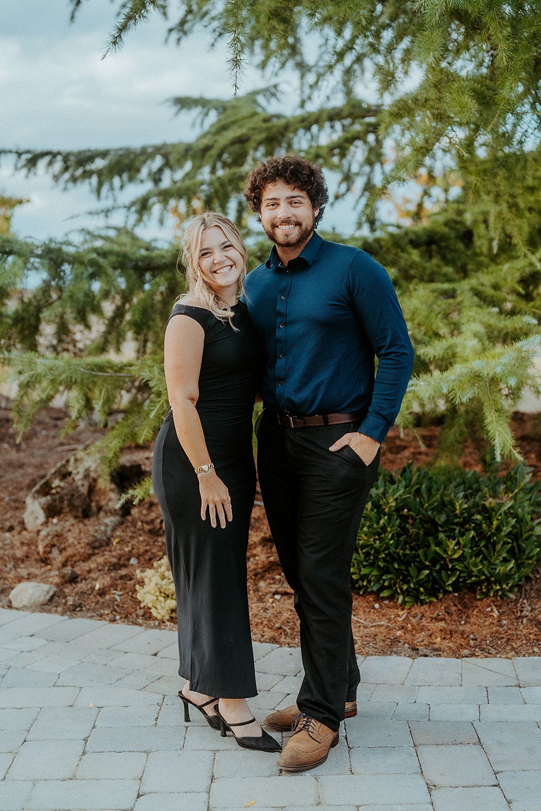 A man and a woman are posing for a picture in front of a tree.