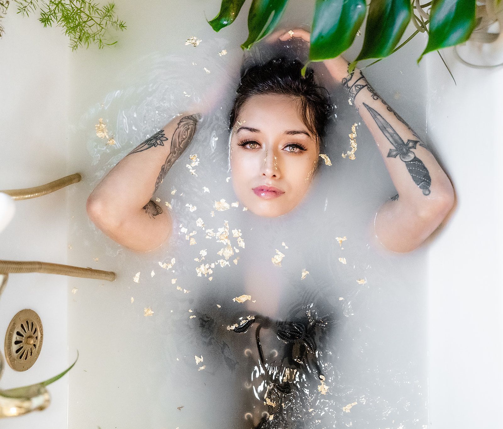 A woman is laying in a bathtub filled with foam and leaves.