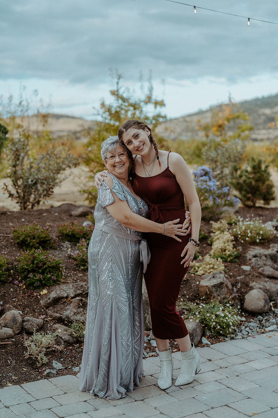 Two women are posing for a picture together while standing next to each other on a patio.