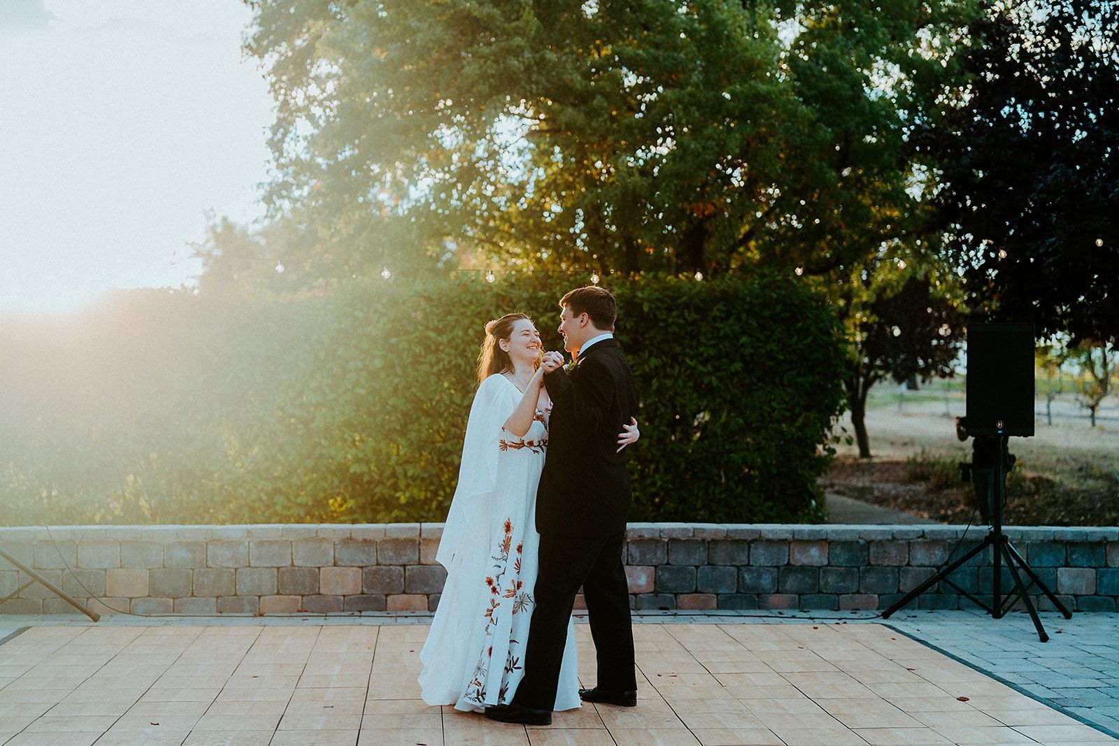 A bride and groom are dancing on a wooden dance floor.